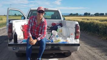 5 - Priscilla sitting in the back of the truck at the Tulelake fields with snacks and samples around her.