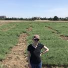 Claire Spickermann standing in a field with rows of short plants extending behind her.